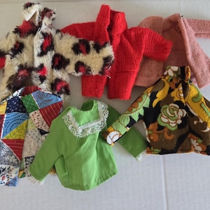 May include: A collection of doll-sized jackets and tops in various colors and patterns. Includes a faux fur leopard print jacket, a red knit jacket, a pink textured jacket, a green top with lace trim, a patchwork jacket, and a floral print jacket.