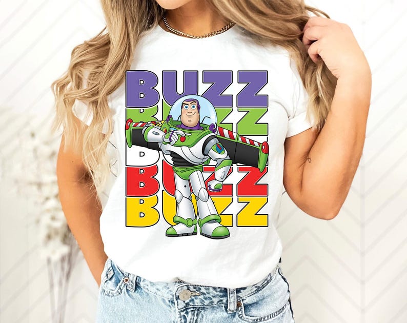 Puede incluir: Camiseta blanca con un gr&aacute;fico de Buzz Lightyear de Toy Story. El dise&ntilde;o incluye la palabra "BUZZ" en letras apiladas y coloridas. Buzz se representa con su traje espacial verde y blanco.