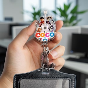 May include: A clear plastic Coco-themed badge reel featuring characters and a guitar design. The reel includes a black dog charm and a black ID holder. The word "COCO" is displayed in colorful letters.