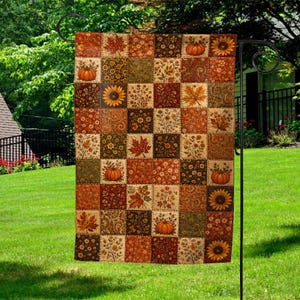 May include: A rectangular garden flag featuring a patchwork design of various autumn-themed squares. The pattern includes illustrations of orange pumpkins, yellow sunflowers, and brown maple leaves set against a background of floral motifs.