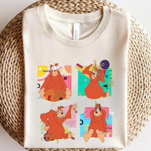 May include: A white t-shirt featuring a colourful graphic print of four cartoon orangutans in various poses. The orangutans are wearing hats and sunglasses and are surrounded by geometric shapes.