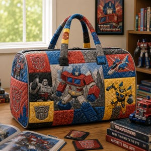 May include: A quilted duffel bag featuring a colorful patchwork design with Transformers characters including Optimus Prime, Megatron, and Bumblebee, alongside Autobot and Decepticon logos. The bag has two fabric handles and a zippered top closure.