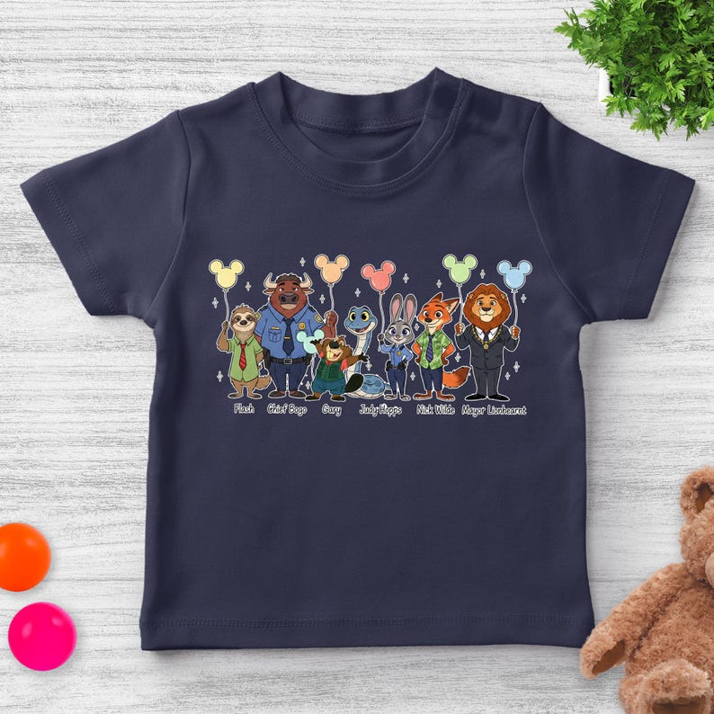 May include: Navy blue toddler t-shirt featuring a colorful graphic of characters from Zootopia, each holding a balloon. The characters include Flash, Chief Bogo, Gary, Judy Hopps, Nick Wilde, and Mayor Lionheart. The names of the characters are printed below them.