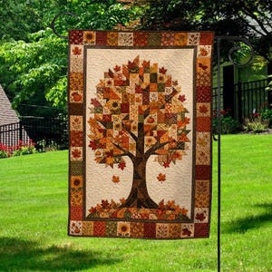 May include: A rectangular garden flag featuring a central tree made of patchwork squares in shades of orange, brown, yellow, and green. The tree is surrounded by a border of small squares with autumn leaf, sunflower, and pumpkin patterns.