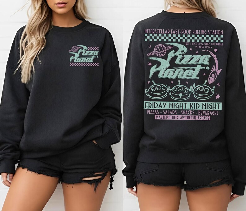 May include: Black sweatshirt with a Pizza Planet graphic on the front and back. The front features the logo, while the back displays the text "INTERSTELLAR FAST-FOOD FUELING STATION" and "FRIDAY NIGHT KID NIGHT" with alien characters.