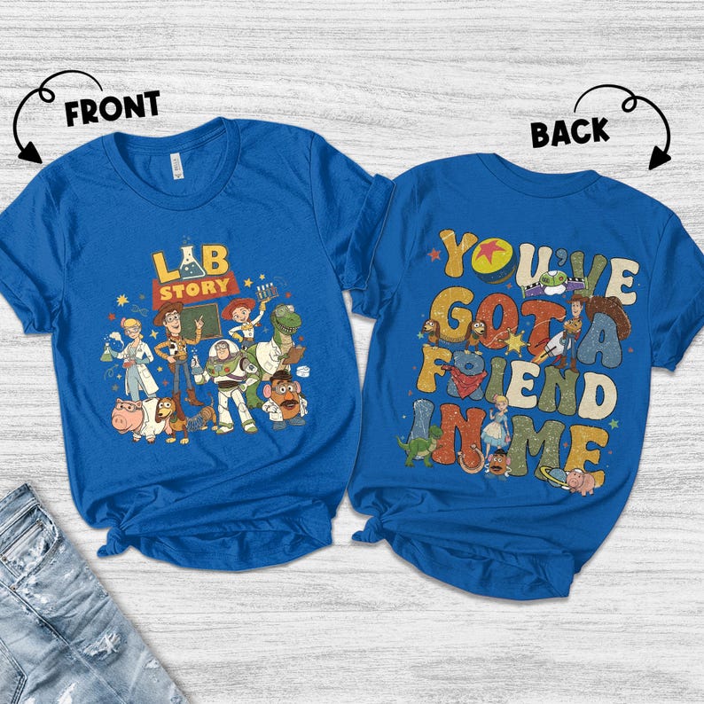 Op de afbeelding: Twee blauwe T-shirts met Toy Story-graphics. Het shirt aan de voorkant heeft de tekst "LAB STORY" met karakterillustraties. Het shirt aan de achterkant zegt "YOU'VE GOT A FRIEND IN ME" met karakterillustraties. Beide shirts zijn korte mouwen.