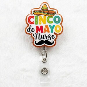 May include: A Cinco de Mayo themed badge reel with a sombrero and mustache design. The badge reel features the text "Cinco de Mayo Nurse" in colorful letters. The badge reel has a clear plastic retractable reel and a metal clip.