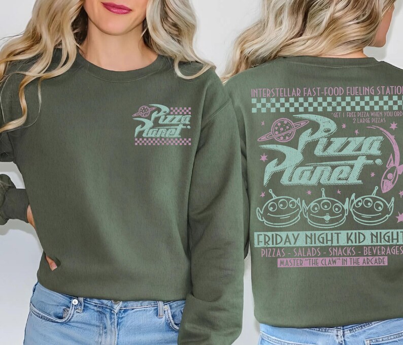 May include: Olive green sweatshirt with the Pizza Planet logo on the front and back. The front features the logo in pink and white. The back has the Pizza Planet logo, aliens, and text in pink and teal.