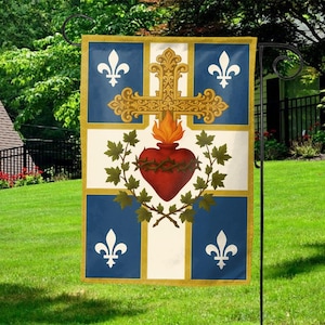 May include: A decorative garden flag featuring a religious design. The flag has a blue and white background with a gold cross, a red heart, and fleur-de-lis symbols. The flag is displayed on a black metal stand in a grassy yard.