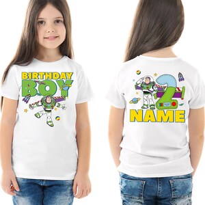 Pu&ograve; includere: Maglietta bianca con una grafica colorata di Buzz Lightyear e la scritta "BIRTHDAY BOY" sul davanti. Il retro mostra un grande numero "2" con la scritta "NAME". Il design include razzi, stelle e pianeti.