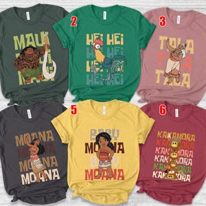 May include: Six short-sleeved t-shirts with character graphics and text from the animated film Moana. The shirts are in various colors, including green, yellow, and maroon. Each shirt features a different character and text.