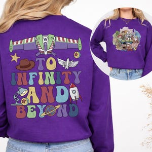 May include: A purple sweatshirt featuring a colorful graphic design from the movie Toy Story. The back of the sweatshirt has a Buzz Lightyear spaceship design, the phrase "To Infinity and Beyond", and other character illustrations. The front has a group of Toy Story characters.