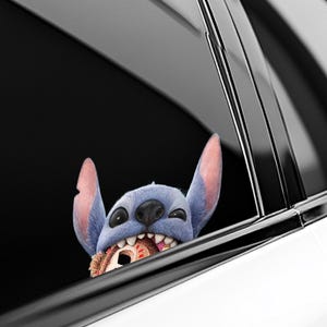May include: A blue cartoon character with large ears and a wide grin, peeking out from a car window. The character is holding a round object in its mouth. The car window is black and the car is white.