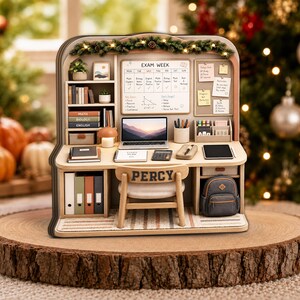 May include: A miniature wooden desk set featuring a laptop, an 'EXAM WEEK' whiteboard, books labeled 'MATH', 'BIOLOGY', and 'ENGLISH', a chair with the name 'PERCY' printed on the back, a backpack, and various office supplies, all decorated with a garland.