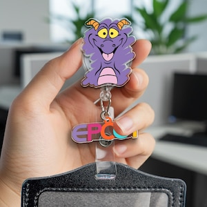 May include: A purple Figment character badge reel with the word "EPCOT" in colorful letters. The badge reel has a clear plastic strap and a black and gray holder.