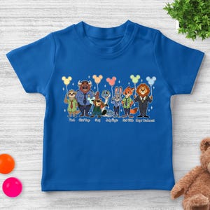 May include: A royal blue toddler t-shirt featuring a colorful graphic of characters from the movie Zootopia. The characters are holding balloons and are labeled with their names. The text at the bottom reads "Flash, Chief Bogo, Gary, Judy Hopps, Nick Wilde, Mayor Lionheart."