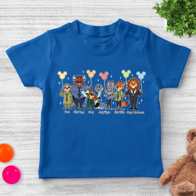 May include: A royal blue toddler t-shirt featuring a colorful graphic of characters from the movie Zootopia. The characters are holding balloons and are labeled with their names. The text at the bottom reads "Flash, Chief Bogo, Gary, Judy Hopps, Nick Wilde, Mayor Lionheart."