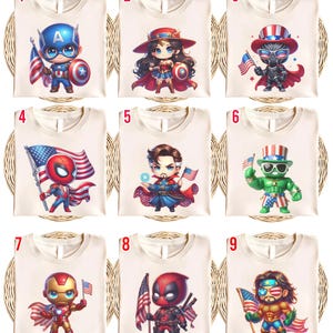 May include: Nine cream-colored t-shirts featuring cartoon superhero characters. Each shirt displays a different character, including Captain America, Wonder Woman, and Iron Man, holding an American flag. The designs are colorful and detailed, perfect for fans of comic books and superheroes.