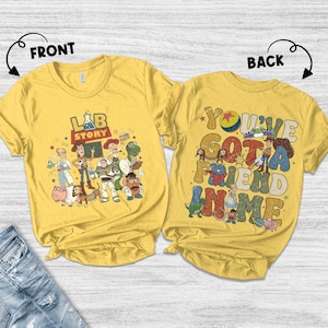 Op de afbeelding: Twee gele T-shirts met cartoonafbeeldingen. Het shirt aan de voorkant heeft de tekst "LAB STORY" met cartoonfiguren. Het shirt aan de achterkant zegt "YOU'VE GOT A FRIEND IN ME" met cartoonfiguren. De shirts zijn gemaakt van zacht materiaal.