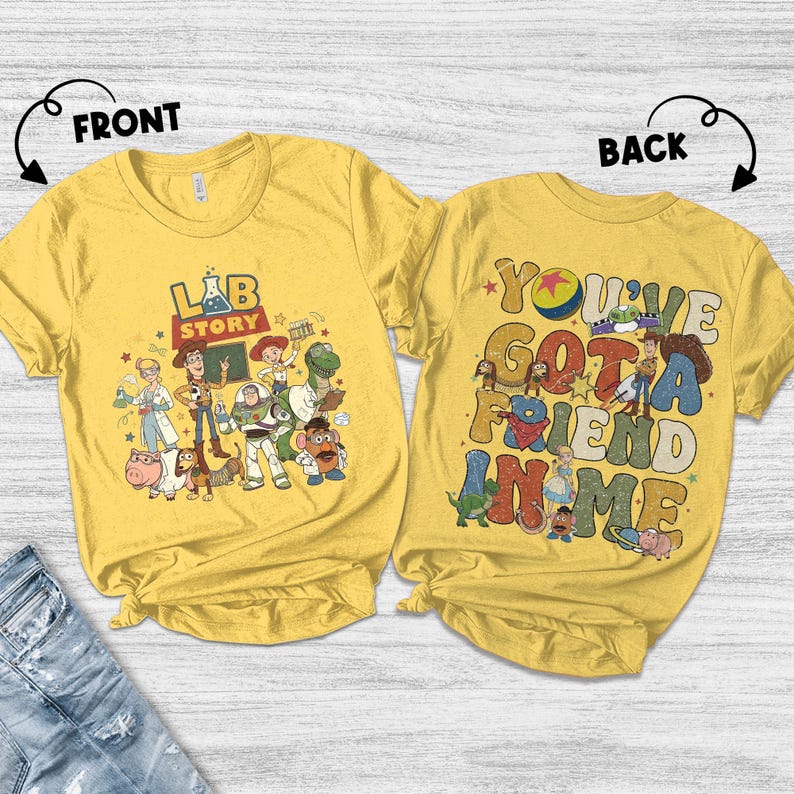 Op de afbeelding: Twee gele T-shirts met cartoonafbeeldingen. Het shirt aan de voorkant heeft de tekst "LAB STORY" met cartoonfiguren. Het shirt aan de achterkant zegt "YOU'VE GOT A FRIEND IN ME" met cartoonfiguren. De shirts zijn gemaakt van zacht materiaal.