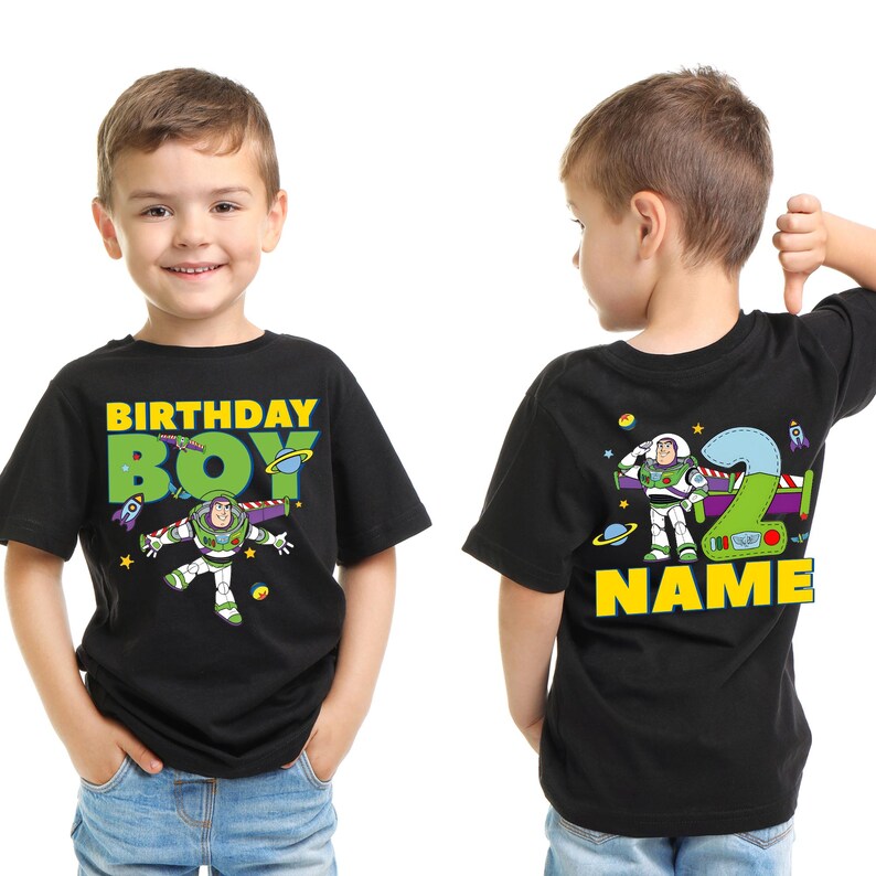 Pu&ograve; includere: T-shirt nera con grafica di Buzz Lightyear e la scritta "BIRTHDAY BOY" in giallo e verde. Il retro della maglietta presenta un grande numero "2" e la parola "NAME" in giallo. La maglietta &egrave; indossata da un bambino.
