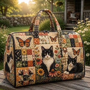 May include: A quilted duffel bag featuring a patchwork design with black and white cats, orange monarch butterflies, and colorful floral patterns. The bag has two top handles, a zippered closure, and a rectangular shape with rounded edges.