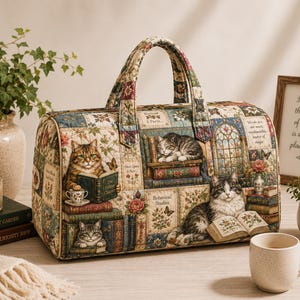 May include: A quilted duffel bag featuring a multi-colored tapestry print of cats, books, and floral motifs. The bag has two top handles, a rectangular base, and a zippered closure. The fabric pattern includes various cats reading books.