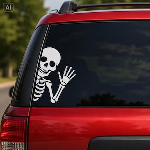 May include: A white vinyl decal of a skeleton torso, head, and arm waving, applied to the rear window of a red vehicle. The skeleton is depicted with a smiling skull, visible rib cage, and an extended hand with fingers spread in a greeting.