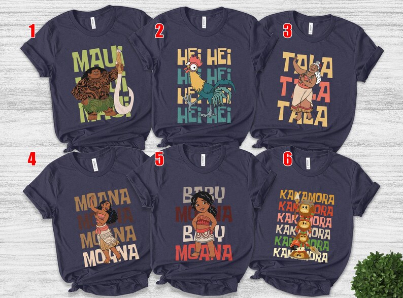 May include: Navy blue t-shirts featuring characters and text from the animated film "Moana." Designs include Maui with a hook, Hei Hei the rooster, Tala, Moana, Baby Moana, and the Kakamora. Each shirt has a unique graphic and text.