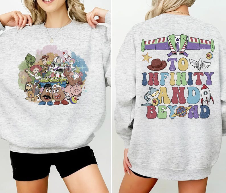 May include: Light gray sweatshirt featuring a colorful graphic of Toy Story characters on the front. The back of the sweatshirt has the phrase "To Infinity and Beyond" with related imagery. A fun and comfortable top for fans of the animated film.