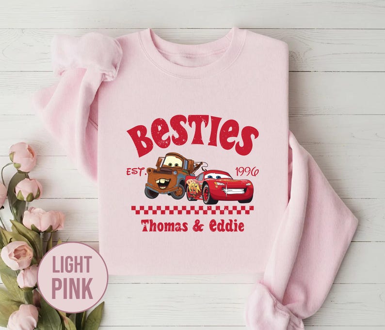 May include: Light pink sweatshirt with the word "Besties" in red script. The design includes cartoon images of two cars, a brown truck and a red race car, with the text "Thomas & Eddie" below.