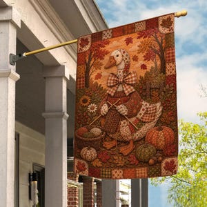 May include: A rectangular garden flag featuring a central illustration of a goose wearing a plaid bow tie and knitting with yarn. The scene includes a basket of yarn, pumpkins, and autumn leaves in shades of orange, brown, and gold, framed by a patchwork border.
