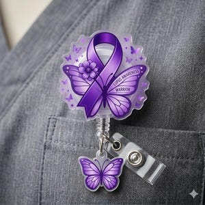 May include: A purple Lupus Awareness badge reel with a butterfly design. The badge features a purple ribbon, a flower, and the words "Lupus Awareness Warrior". A smaller butterfly charm hangs below.