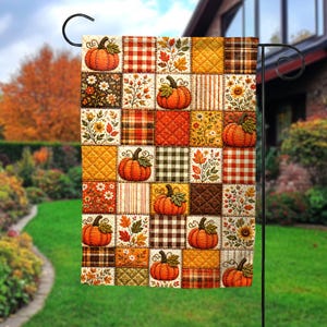 May include: A rectangular garden flag featuring a patchwork design of autumn-themed squares. The pattern includes orange pumpkins, fall leaves, sunflowers, and various plaid and quilted textures in shades of orange, brown, yellow, and cream.