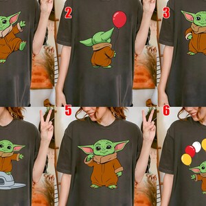 May include: Dark gray t-shirts featuring a cartoon character in various poses. The character has green skin, large ears, and is wearing a brown outfit. Some shirts show the character with a red balloon or floating with balloons.