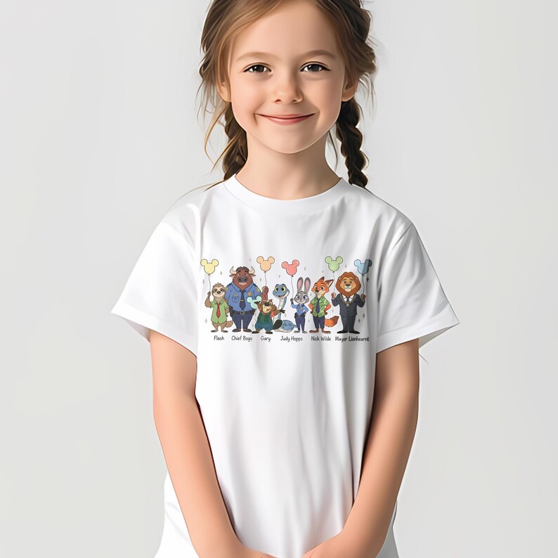 May include: White t-shirt featuring a colorful graphic of characters from the movie Zootopia, including Flash, Chief Bogo, Gary, Judy Hopps, Nick Wilde, and Mayor Lionheart. The characters are arranged in a row with balloons above them. The names of the characters are printed below.