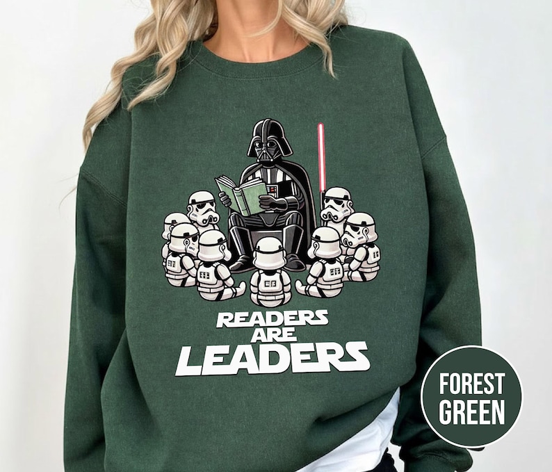 K&ouml;nnte beinhalten: Forstgr&uuml;nes Sweatshirt mit einer Grafik von Darth Vader, der Stormtroopern vorliest. Der Text "Readers Are Leaders" ist in Wei&szlig; gehalten. Ein rotes Lichtschwert ist ebenfalls im Bild zu sehen.