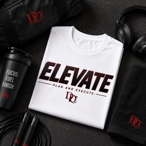 May include: A white t-shirt with the black and red text ELEVATE PLAN AND EXECUTE and a logo, surrounded by a black gym bag, black headphones, a black shaker bottle with the text FOCUS FUEL FINISH, a black towel, and a black jump rope.