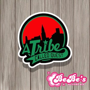 May include: A Tribe Called Quest sticker with a red and black cityscape design. The sticker is round and has a white border. The text "A Tribe Called Quest" is written in green cursive.