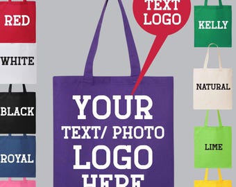 May include: A purple tote bag with white text that reads "YOUR TEXT/PHOTO LOGO HERE". The bag is shown with other tote bags in various colors, including red, white, black, royal blue, azalea, kelly green, natural, lime, and yellow.
