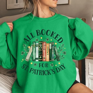May include: Green sweatshirt with the text "All Booked for St. Patrick's Day" and a stack of books with shamrock designs.