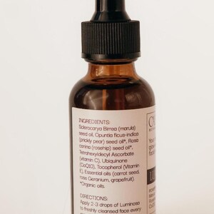 May include: A brown glass bottle with a black dropper top. The label lists ingredients like marula seed oil and rosehip seed oil. The text on the label says to apply 2-3 drops of Luminosa to the face for glowing skin.