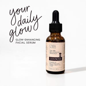 May include: A brown glass bottle of facial serum with a black dropper. The label reads "Luminosa" and "Your daily glow-enhancing facial serum." The text "your daily glow" is written in cursive. The bottle contains 1 oz / 30 mL of product.