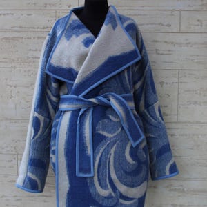 Pode incluir: Um casaco azul e branco estampado, com gola de xale e cinto de laço. O casaco tem uma bainha azul.