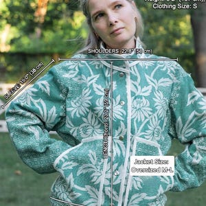 May include: An oversized M-L jacket in teal and white with a floral pattern, featuring a front button closure and white trim. Measurements include a 15.0 inch sleeve, 22.8 inch shoulders, 23.2 inch front length, and a 17.7 inch bottom band.
