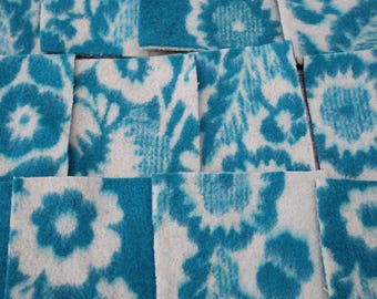 May include: A close-up of a white fabric with a blue floral pattern. The fabric is cut into squares and arranged in a grid pattern.
