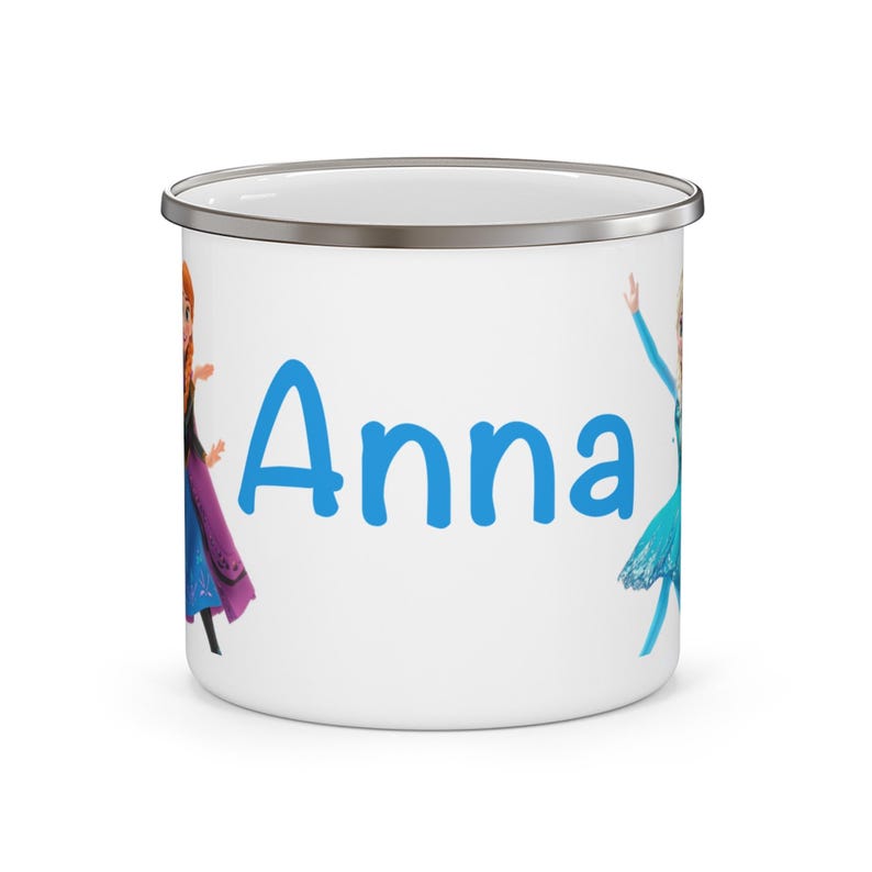 May include: White enamel mug with a silver rim featuring the name "Anna" in blue. The mug is decorated with cartoon images of Anna and Elsa from the movie Frozen. A fun and colorful gift for fans of the animated film.