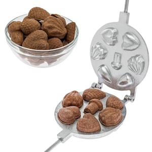 Op de afbeelding: Een zilveren metalen mal voor het maken van chocolade snoepjes. De mal heeft acht verschillende vormen, waaronder harten, schelpen en eikels. De mal is open en gevuld met chocolade snoepjes.