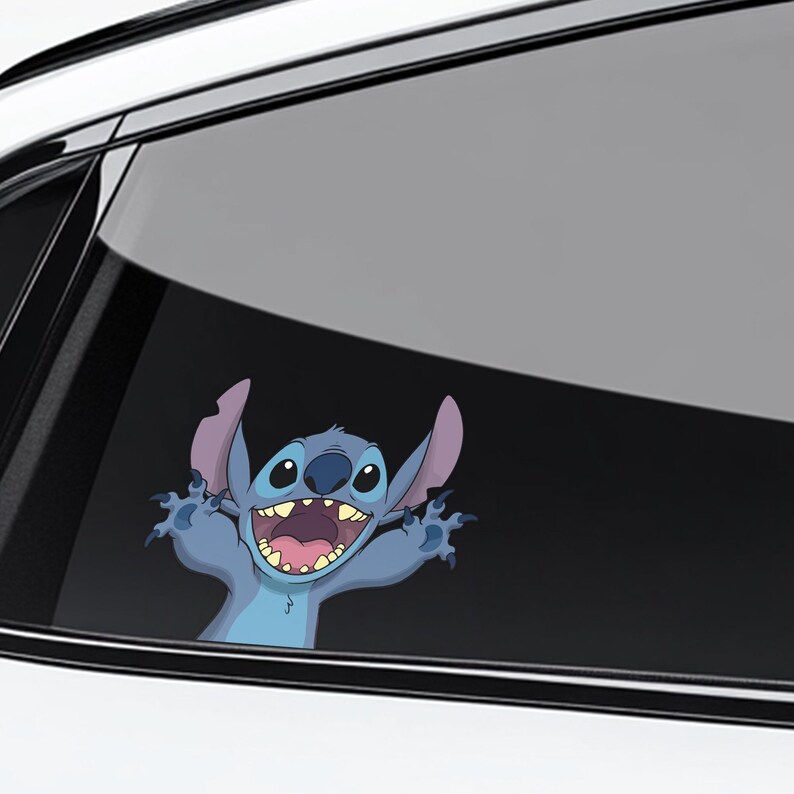 May include: A blue cartoon character sticker, featuring Stitch from Lilo & Stitch, is applied to a car window. The character has large ears, a wide grin, and outstretched arms, creating a playful and friendly appearance.