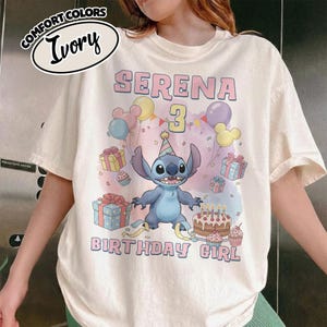 Peut inclure: Un t-shirt ivoire avec une illustration du personnage Stitch portant un chapeau de f&ecirc;te, entour&eacute; de cadeaux color&eacute;s, de ballons et d'un g&acirc;teau d'anniversaire avec des bougies. Le texte indique SERENA, 3, et BIRTHDAY GIRL en lettres roses et bleues.
